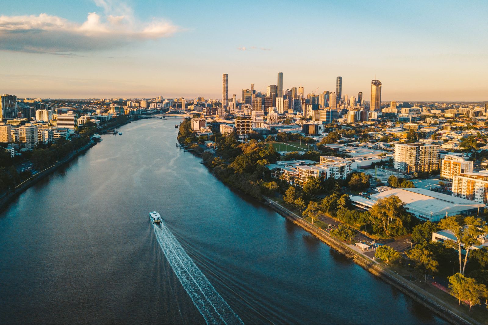 Sunset aerial shot of Brisbane as a City Cat heads towards the city on the Brisbane River