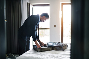 Business traveler packing suitcase in hotel