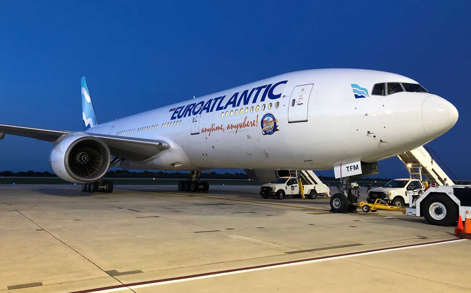 Boeing B777-200 private aircraft charter on runway with boarding ramps and vehicles